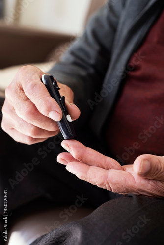 senior man measuring his blood glucose level