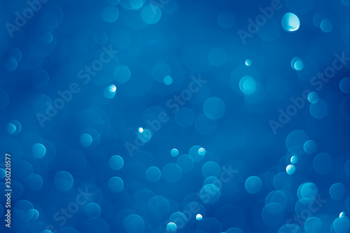 Blue glitter vintage lights background. Blue bokeh on black background.