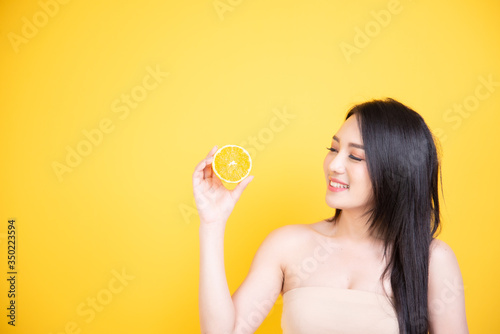 Beautiful Asian women smile happyness holding fresh orange slide with a yellow background.Squeeze Fresh oranges healthy fruits that are vitamin C.