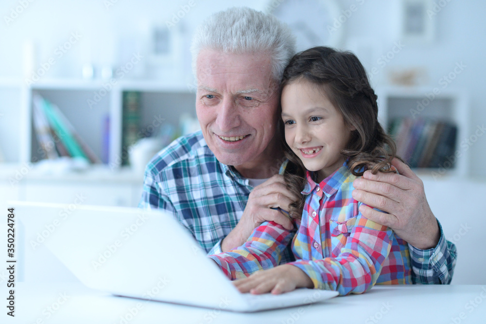 Emotional senior man with granddaughter using laptop at home Emotional senior man with granddaughter using laptop at home