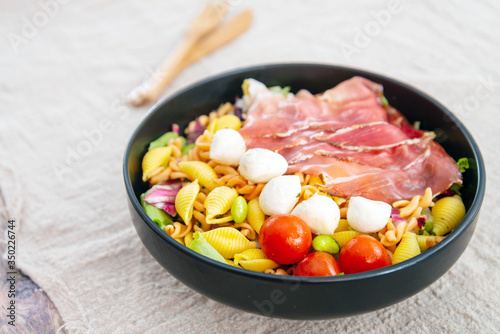 Salad made with cooked pasta, mixed green salads, cherry tomatoes, Mozzarella cheese and smoked ham served with accompaniment