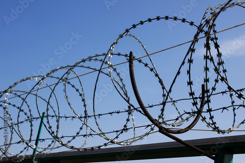 Barbed wire close up on fence with blue sky on the background