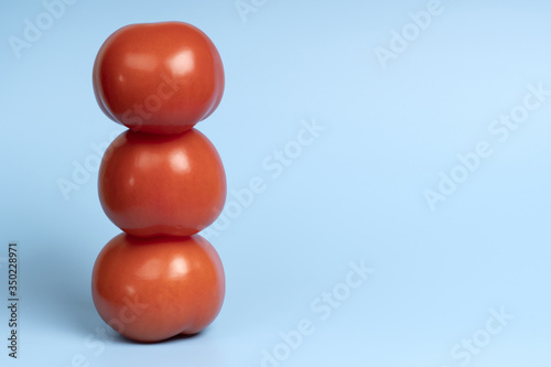 Three organic tomatoes stand in a column