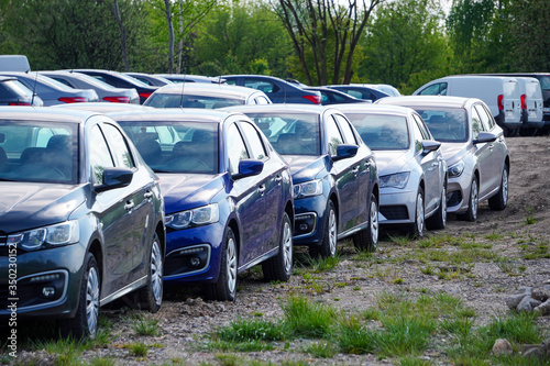 Identical blue cars stand in a row in a Parking lot or market for sale. View of the side mirrors, the Dealership. New car sales. Receiving a car on Commission. Global auto industry crisis