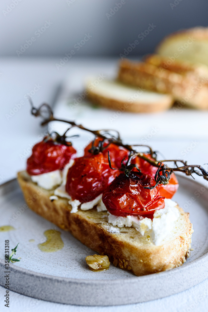 Tomato confit and goat cheese bruschetta on grey concrete table. Selective focus