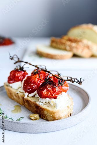 Tomato confit and goat cheese bruschetta on grey concrete table. Selective focus