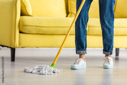 Obraz na płótnie Cropped view of woman mopping floor with mop in living room
