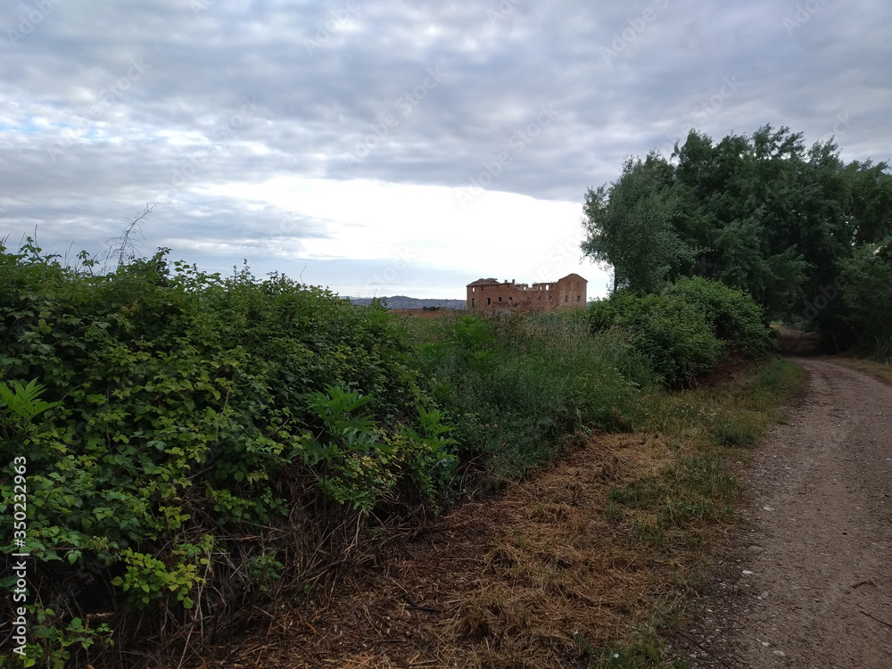 Paisaje con camino de campo y al fondo un edificio en ruinas Paisaje con camino de campo y al fondo un edificio en ruinas