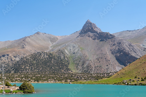 The Pamir range view and peaceful campsite on Kulikalon lake in Fann mountains in Tajikistan. Amasing colorful reflection in pure ice lake. photo