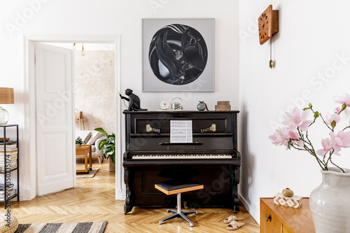 Stylish and cozy interior of living room with black piano, furniture, plant, wooden clock, lamp, mock up painitngs, carpet, decoration and elegant personal accessories in modern home decor.
