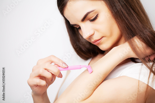 Pretty woman uses a razor to remove hair