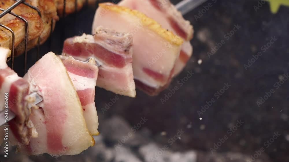 Slowmotion. Close up. Beautiful juicy bacon. Cooking bacon on skewers / grill. Cooking bacon. B-B-Q. Brazier. Tasty bacon.