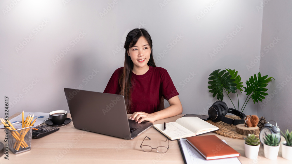A young, beautiful relaxing business asian girl use a laptop working remotely from home on desk as a freelancer, quarantine for Coronavirus and smart working concept. A young, beautiful relaxing business asian girl use a laptop working remotely from home on desk as a freelancer, quarantine for Coronavirus and smart working concept.