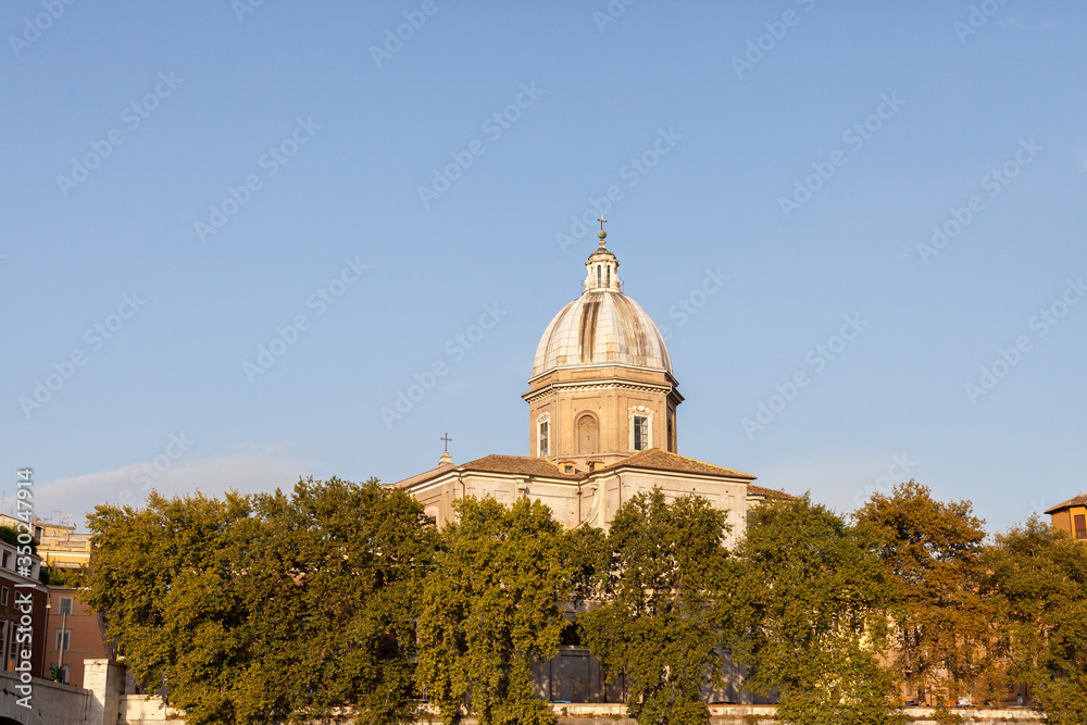 ROME, ITALY - 2014 AUGUST 19. Church dome above the green trees in evening light.
