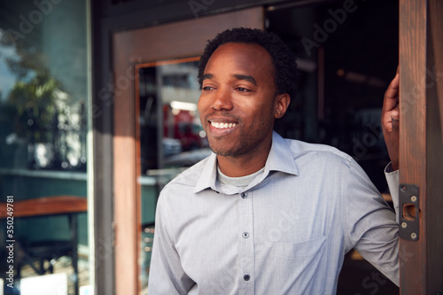 Male Owner Of Start Up Coffee Shop Or Restaurant Standing In Doorway