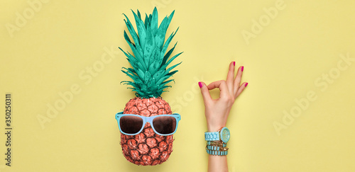 Fashion. Pineapple hipster in sunglasses, sfemale hand, OK gesture. Minimal concept, summer tropical pineapple. Creative art fashionable concept. Summertime color, pineapple OK banner photo