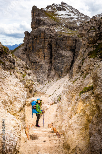 Tourist woman hiking mountain alpine canyon trail cliffs, South Tyrol, Italy.
