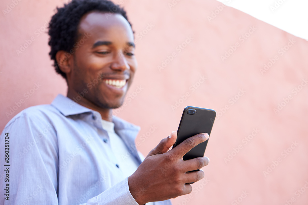 Outdoor Portrait Of Man Using Mobile Phone In The Street Leaning Against Wall Outdoor Portrait Of Man Using Mobile Phone In The Street Leaning Against Wall