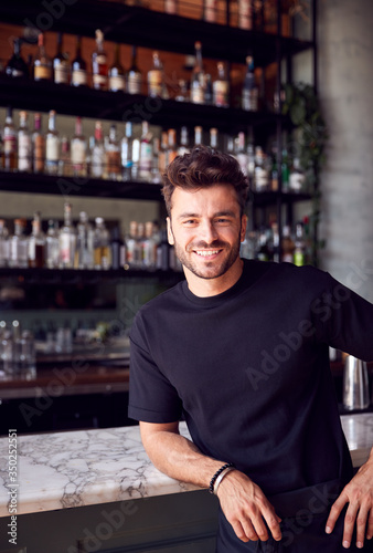 Portrait Of Confident Male Owner Of Restaurant Bar Leaning Against Counter