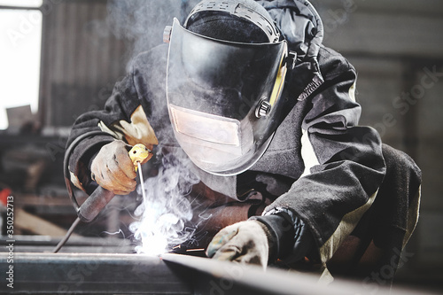 Welder working with welding on metal frames in an industrial plant. photo