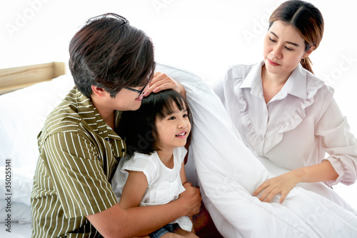 Happy family having fun in the bedroom. Father, mother and daughter spending time together, parents and kid having good memory and playing together at home