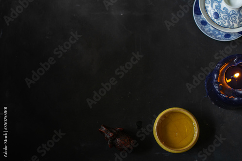 A cup of Chinese tea, teapot, candle, wooden elephant on a black background