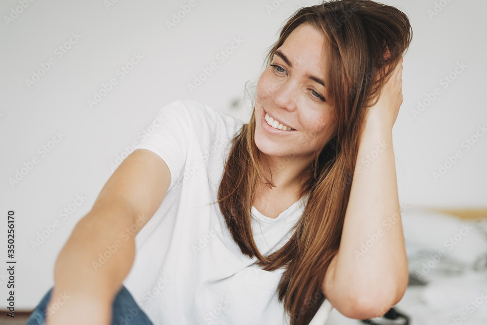 Portrait of smiling young woman brown hair and green eyes with freckles in the white t-shirt and jeans Portrait of smiling young woman brown hair and green eyes with freckles in the white t-shirt and jeans