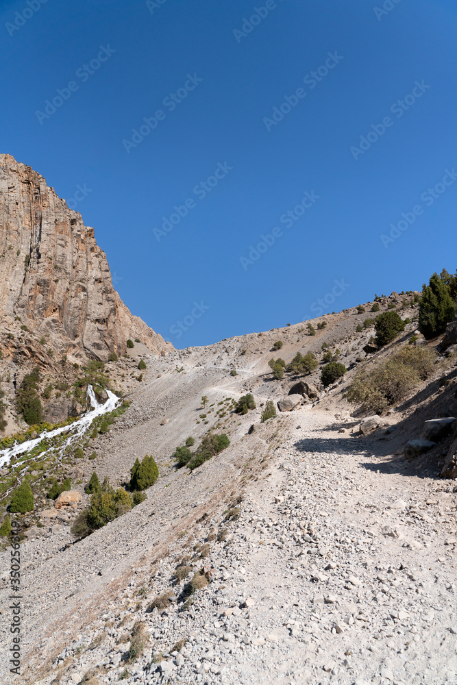 The beautiful mountain trekking road with clear blue sky and rocky hills in Fann mountains in Tajikistan