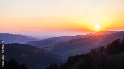 Germany, Romantic orange sunset sky over mountains silhouette in nature landscape of black forest scenery with view from lindenberg mountain © Simon