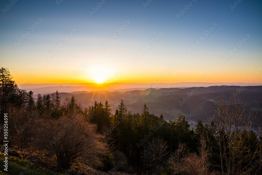 Germany, Romantic orange sunset sky with sunrays over vosges mountains nature landscape view from hoernleberg mountain at dawn