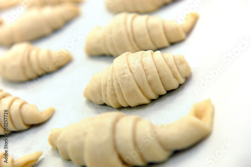 croissants that are rising on a white table before being baked in a pastry shop
