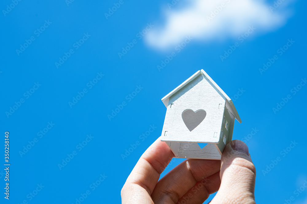 Man holding small white model of house against sky background Man holding small white model of house against sky background