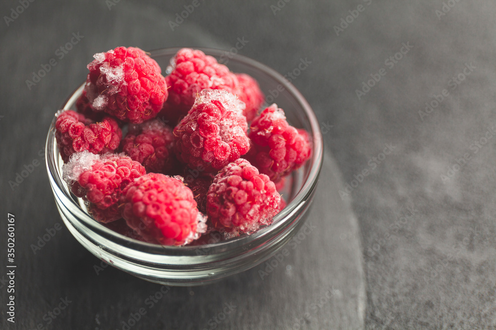 Frozen raspberries in plate on black table. Winter vitamin dessert. Frozen raspberries in plate on black table. Winter vitamin dessert.