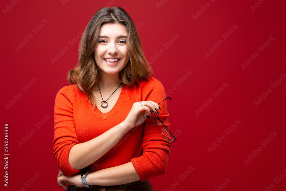 Cheerful young girl student with a smile, isolated on a red background. The concept of happiness and positive Cheerful young girl student with a smile, isolated on a red background. The concept of happiness and positive