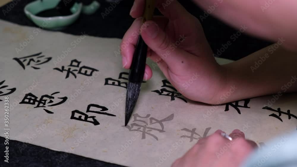 Young woman practicing Chinese traditional calligraphy at home