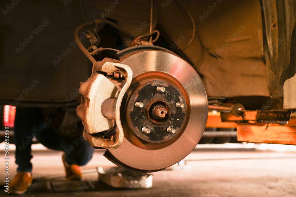 Front car brake disc and brake pads after replacement in the car repair shop.