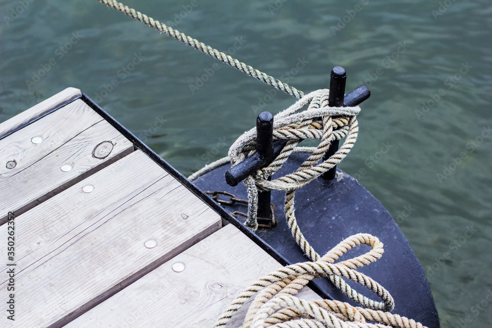 Obraz premium Ship line moored to the mooring post on a modern wooden jetty hobby safety pile group risk of tripping pier expert knowledge
