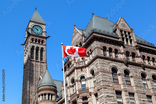The waving Canadian flag at Old City Hall in background in Toronto, Canada. Toronto is the provincial capital of Ontario and the most populous city in Canada. 
