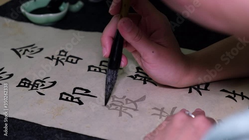 Young woman practicing Chinese traditional calligraphy at home photo