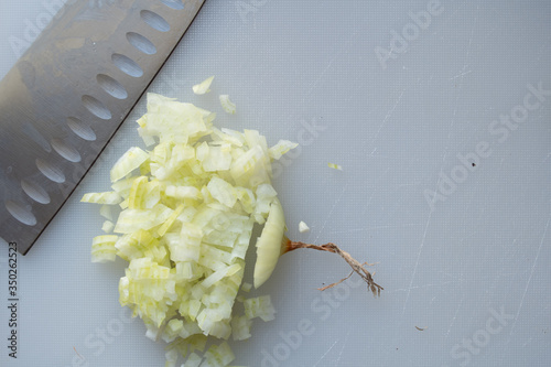 Onion on white cuttingboard with a knife nex to it. chopped onion