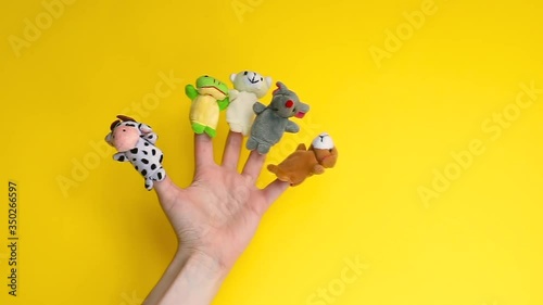 Puppet theater doll animals. Hand wearing finger puppets: cow, frog, dog, rabbit, mouse, bear. animal finger puppets show isolated on yellow background. family quarantine fun. template mock up. 