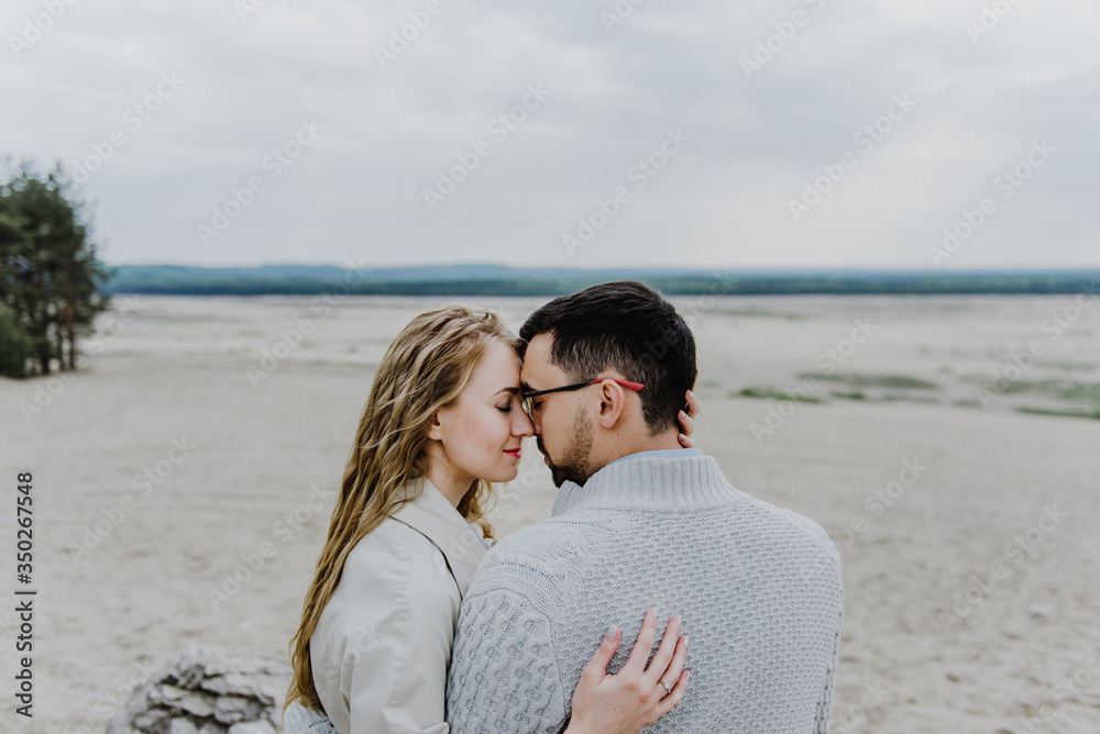 Young woman and man hug and kiss in a sand quarry.