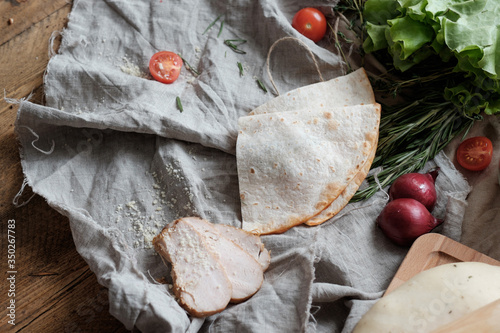 Quesadilla with chicken and ingredients on wooden table on dark rustic background