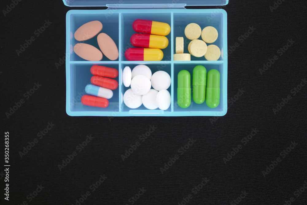 bunch of different medications, tablets, pills and capsules on a black matte background. bunch of different medications, tablets, pills and capsules on a black matte background.