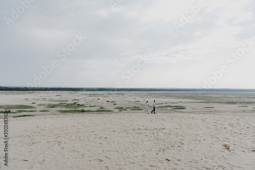 A young woman and a man walk, hug and kiss in a sand quarry.