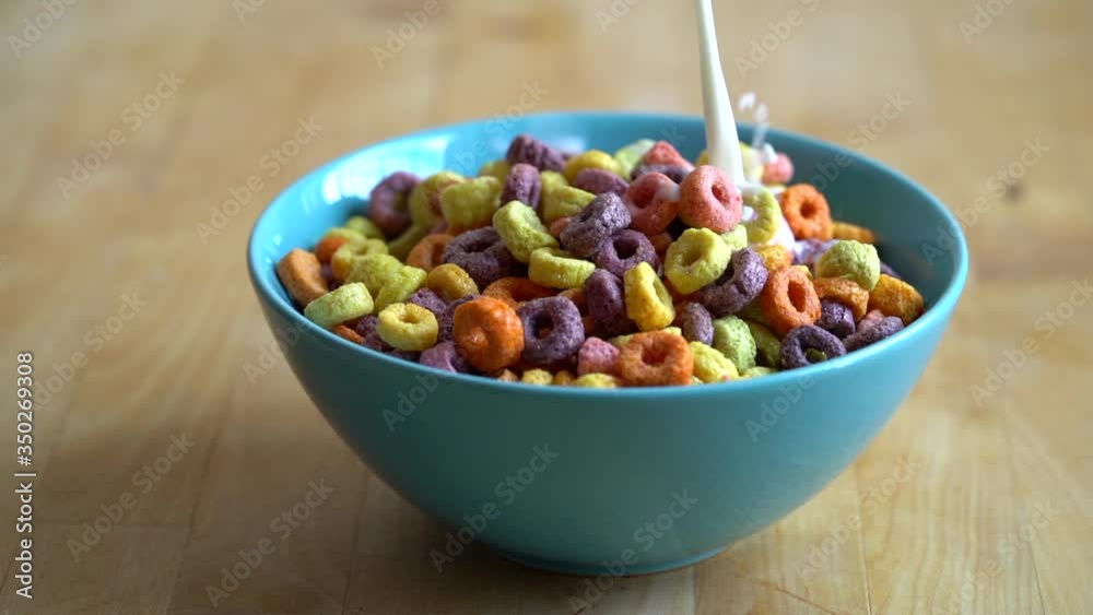 Milk pouring into colourful bowl of cereal, slow motion. Milk pouring into colourful bowl of cereal, slow motion.