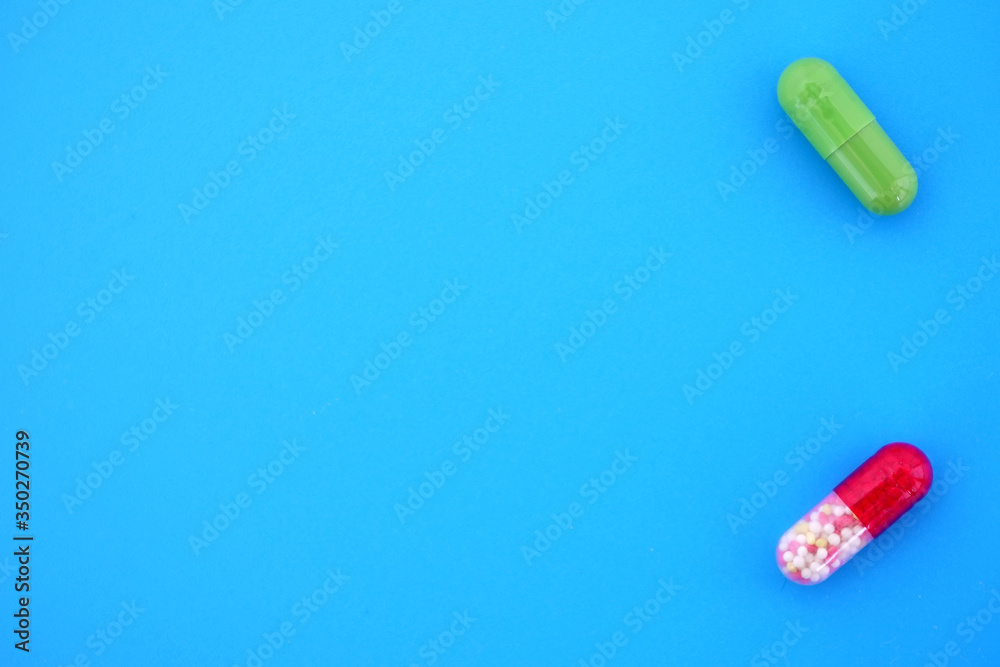 Two bright medical capsules on a bright blue isolated background with space for text. Two bright medical capsules on a bright blue isolated background with space for text.