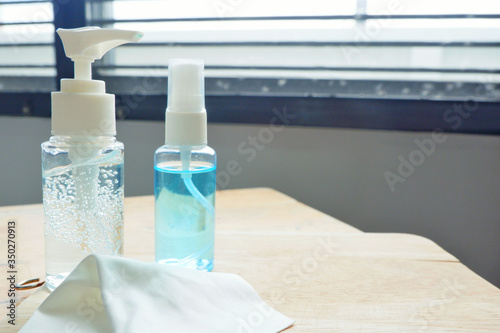 Alcohol gle and a white cloth on wood shelf.Alcohol gel bottle for protect bacterial and anti virus (COVID19).Close up. photo