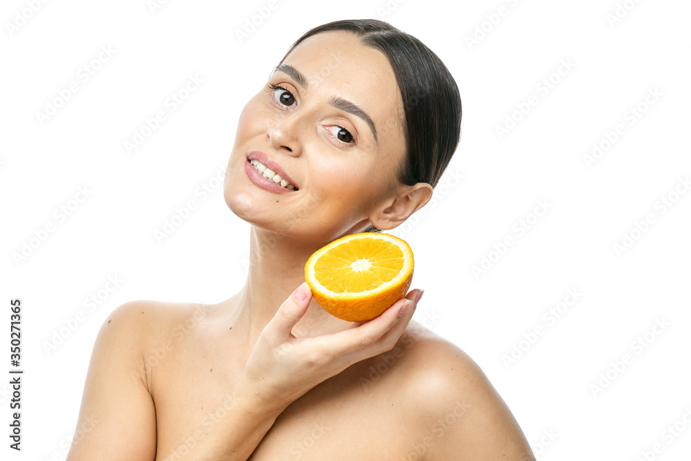 close-up portrait of a young girl with clear skin, holding an orange on a white background close-up portrait of a young girl with clear skin, holding an orange on a white background