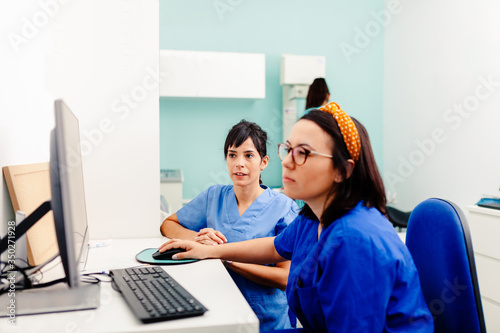 Two nurses using a computer in a x-ray room